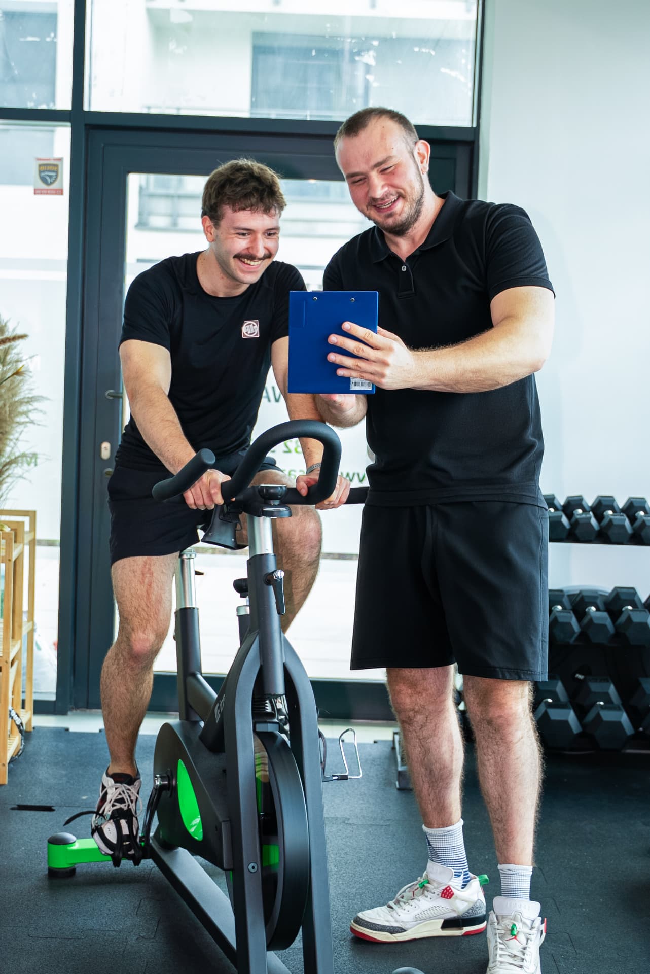 Trener omawia plan treningu wdrożeniowego z klientem w studiu na Mokotowie